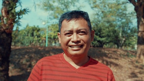 Bali Ubud , Indonesia / Indonesia - 10 16 2019: Balinese farmer man portrait. He is standing in the tropical forest in a hot sunny day. He smiles.