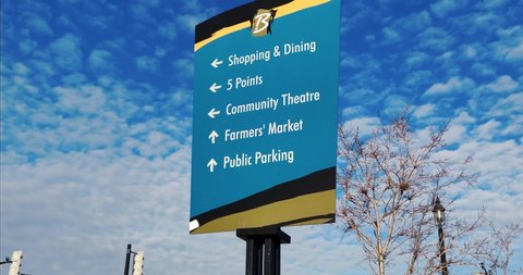Community Downtown Location Sign giving Direction towards important local Landmarks during Beautiful Summer day