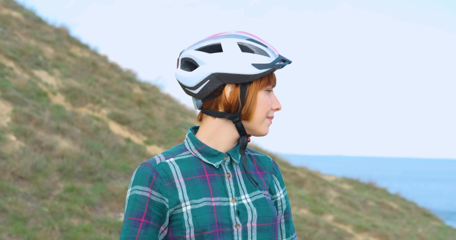 portrait of young woman in bicycle helmet with blue sky on background	