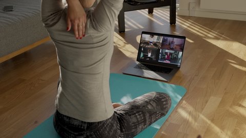 Fitness coach teaching yoga online to group of people. People practicing yoga with trainer via video conference.
