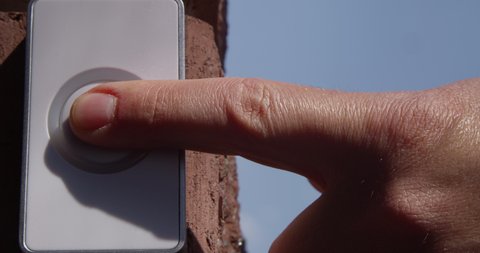 Pressing Doorbell with Man and Woman Finger and Red Nails on a Blue Sky on Sunny Day