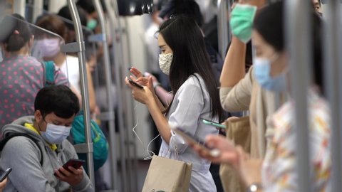 Bangkok,Thailand-April 24,2020: Slow motion Commuters on BTS Sky train in Bangkok sitting and standing far apart with face mask as part of social distancing to combat coronavirus or covid-19 outbreak.