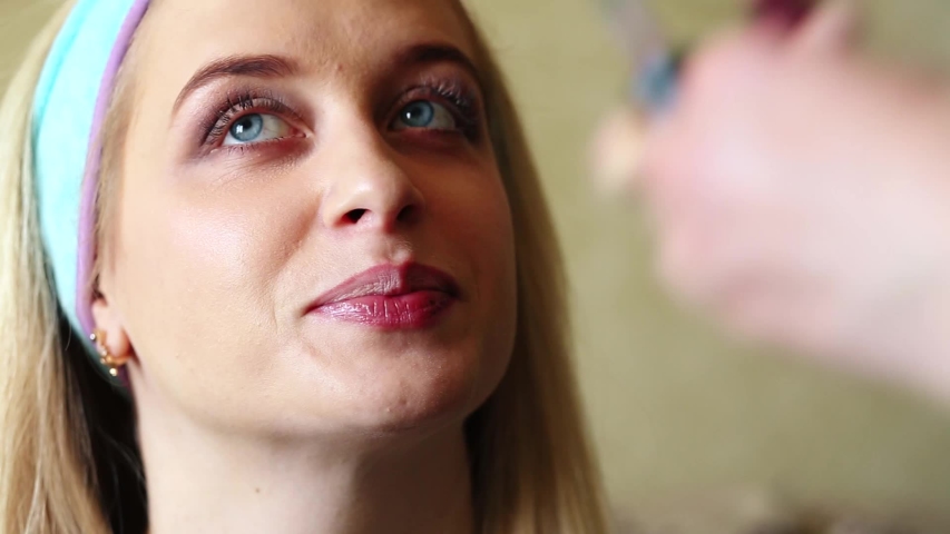 Makeup artist does makeup to a girl, paints her lips
