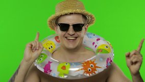 Shirtless young happy man tourist with swimming ring celebrates and dances. Portrait of blonde guy in hat and sunglasses isolated on chroma key background. Place for your logo or text - Powered by Shutterstock - Get 15% off with code: PIKWIZARD15