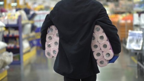 Man walking in medical mask with toilet paper shopping bags during the quarantine coronavirus COVID-19 pandemic in 2019-2020 coronavirus quarantine.