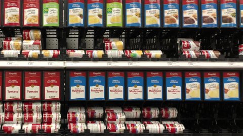 Alameda, CA - May 5, 2020: 4K HD Video panning across grocery store shelf with cans of various flavors Campbells soups. Campbell Soup Company, selling products in 120 countries around the world