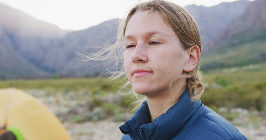 Caucasian woman having a good time on a trip to the mountains, camping in nature, enjoying a view and wearing warm clothes, in slow motion 