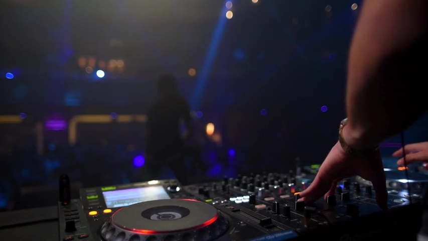 DJ in a night club works, mixes music with a remote control Royalty-Free Stock Footage #1051914103