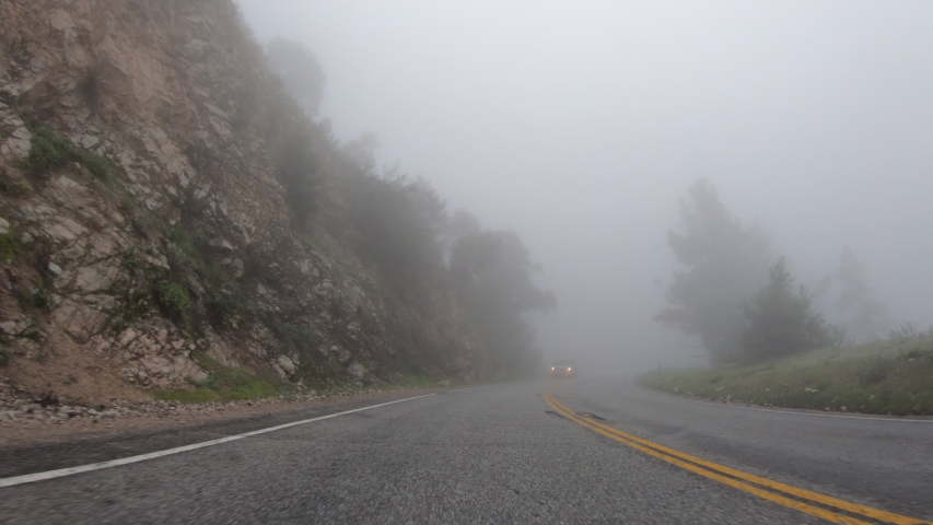 Driving rear view through fog and clouds on Angeles Crest Highway in the San Gabriel Mountains near Los Angeles in Southern California.