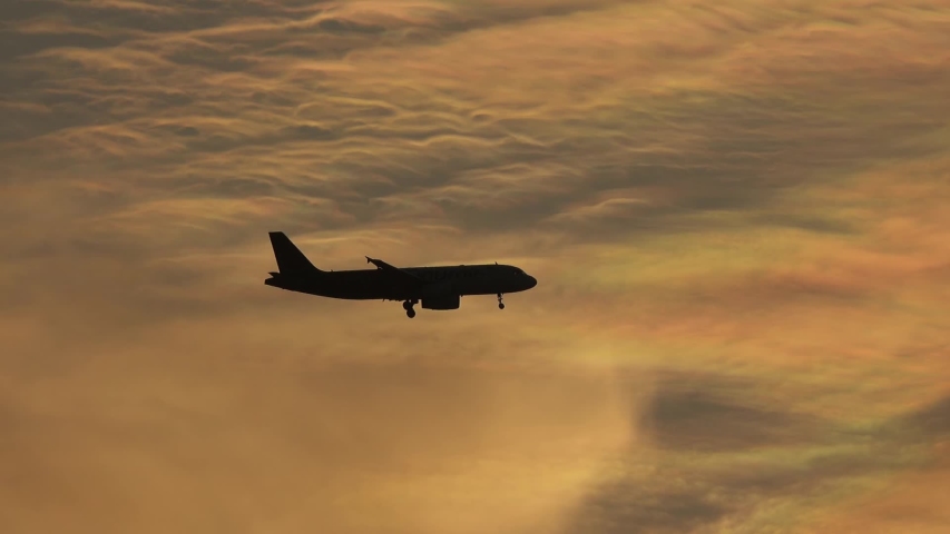 Silhoutte of plane flying over sunset sky background