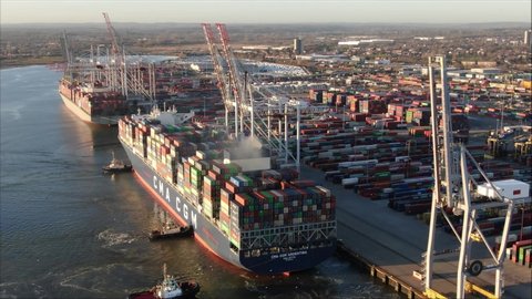 Southampton / United Kingdom (UK) - 01 28 2020: Aerial orbit shot of large container ship in port. Tugs pushing ships into place, logistics, import and export from the UK.