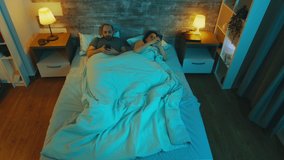Top view of couple in the bedroom late at night using their phones.