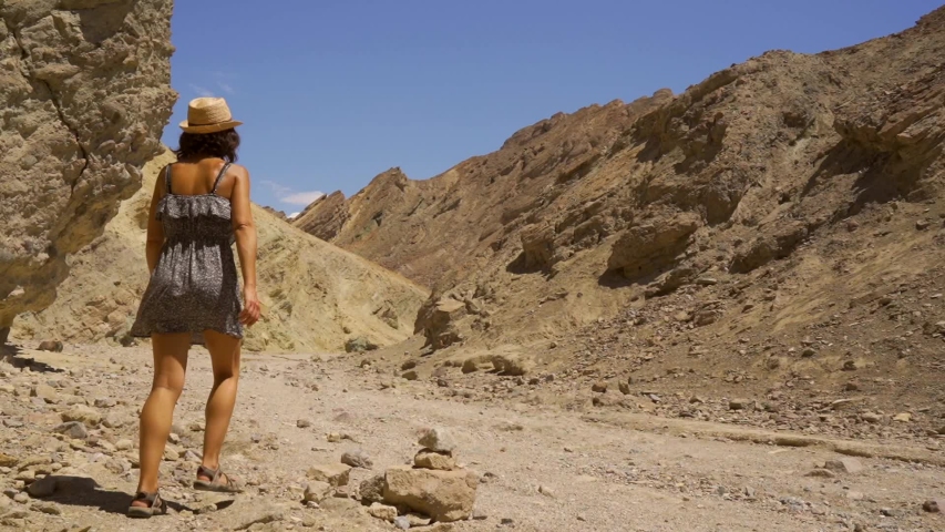 A young woman in dress on the Golden Canyon trail in Death Valley, California. United States