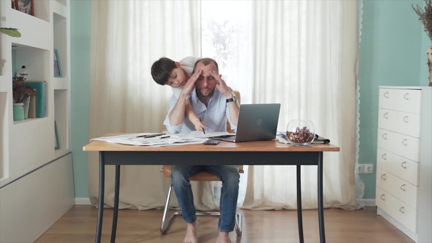 SLOW MOTION. Parent working from home. Remote work. Family on self-isolation. Home office. A man is working at a table. The son interferes with the father's work. Dad gets annoyed. Quarantine Epidemic Royalty-Free Stock Footage #1051953103