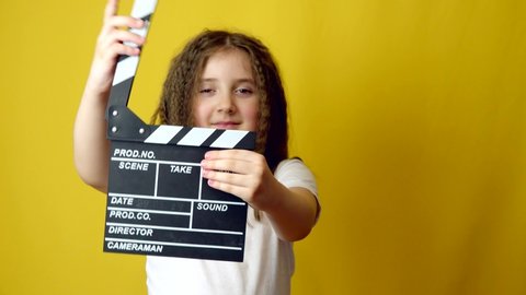 Funny smiling child girl hold film making clapperboard. Copy space for text