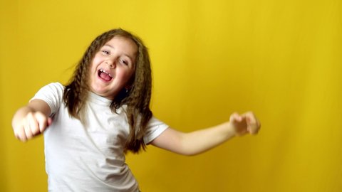Happy and Joyful Little 6 years old Kid Jumping on yellow Background.