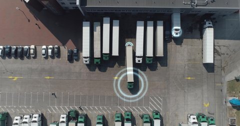 Buildings of logistics center near the highway, the truck leaves parking, artificial intelligence tracks trucks, motion graphics, view from height, a large number of trucks in the parking lot near