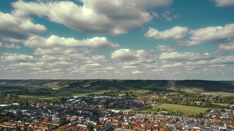 Aerial time lapse of English rural town in beautiful countryside setting under cumulus clouds 