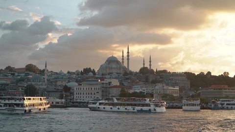ISTANBUL, TURKEY, May 23rd 2018: A passenger ferry sails across the frame from Eminonu port with the Golden Horn and Suleymaniye Mosque in the background at dusk.
