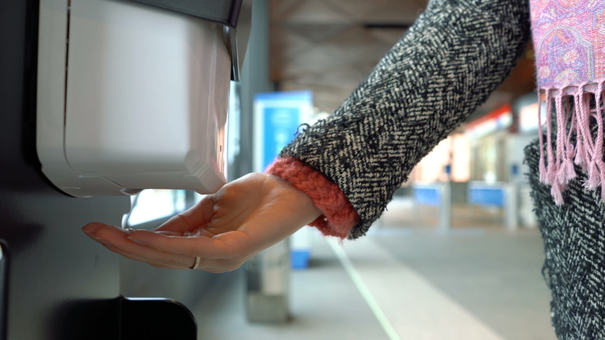 Metro passengers using a public dispensary with hand sanitizer at a metro station in Finland.
