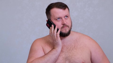 fat naked bearded man talking on the phone, getting bad news, shocked insane evil gesture