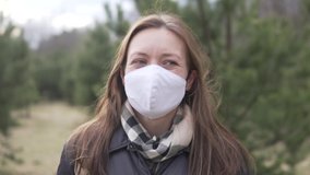 A woman removes a protective mask from her face and takes a deep breath in the woods - Powered by Shutterstock - Get 15% off with code: PIKWIZARD15