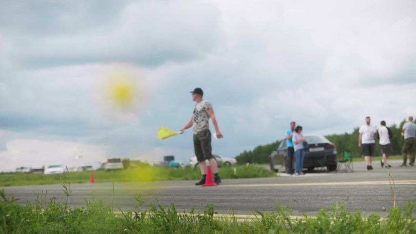 A purple sports car rolls onto the starting line in cloudy weather.