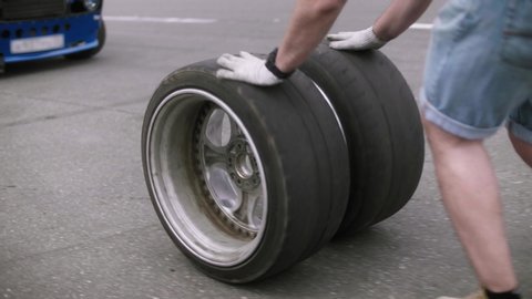 Mechanic rolls two new, freshly assembled wheels along the road close-up shot