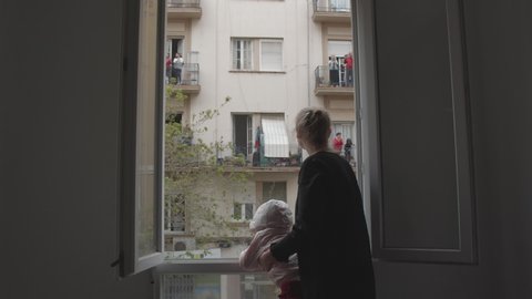 People from neighboring houses coming out to balconies and looking from open windows to give applause to health workers for their job during coronavirus pandemic
