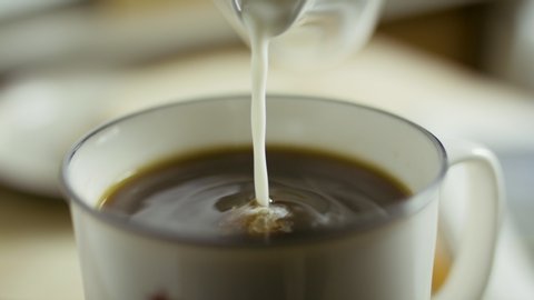 Cream pouring into black morning coffee. Coffee mug. Slow-motion product clip. Shot on RED camera in 4k. Free preview.