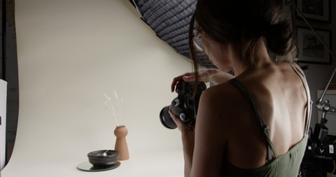 Product photographer taking photos in home studio - close up form behind