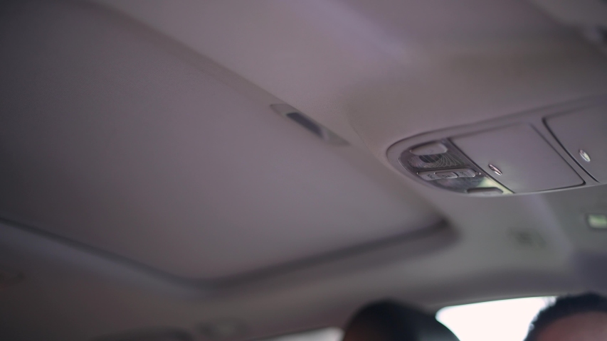 The girl presses the button to open the hatch in the car and the hatch opens, showing bright light from the sky. No face, close up Royalty-Free Stock Footage #1052005828