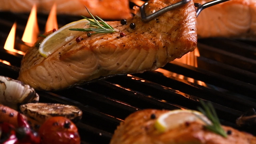 Grilled salmon fish with various vegetables on pan on the flaming grill Royalty-Free Stock Footage #1052007502