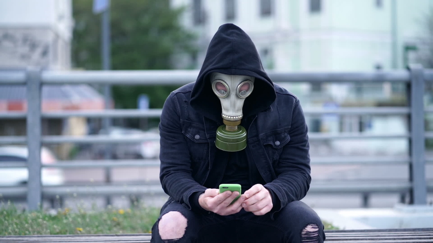 Man with respirator sitting on the bench with mobile phone. Slowmotion. | Shutterstock HD Video #1052011480