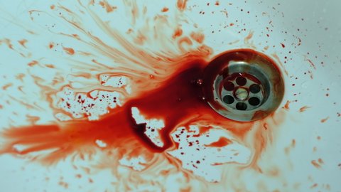 human blood slowly drips and spreads over a clean white washbasin