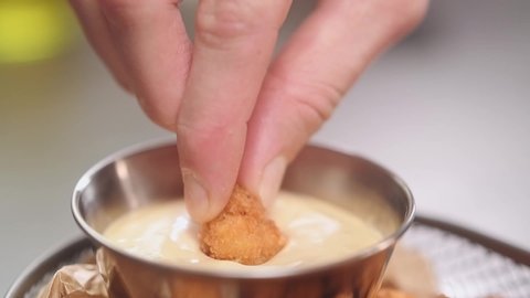 Fried chicken nuggets are dipped in sauce, slow motion.