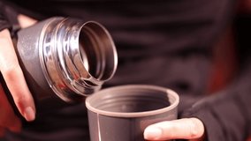 Video footage, female hands pour coffee from a thermos into a mug