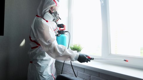 Woman making disinfection on windows. professional cleaning service worker in protective suit and rubber gloves disinfects windows with disinfectant and sponges. Coronavirus disinfection.