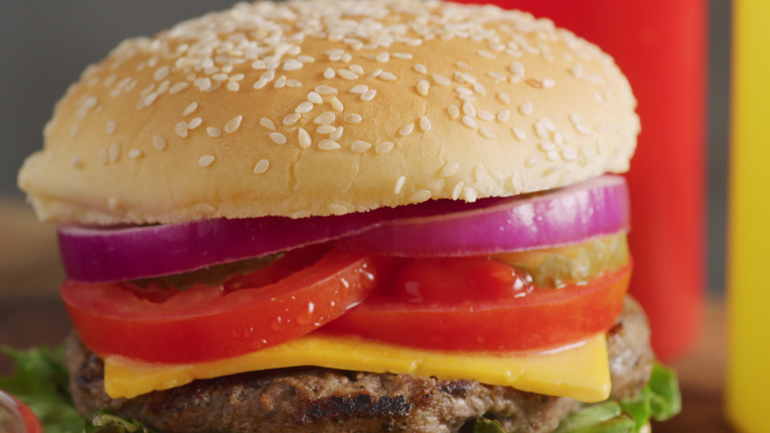 Closeup shot of fresh hamburger with cheese, lettuce, tomato, onion and pickle. Shot on RED 8K camera.