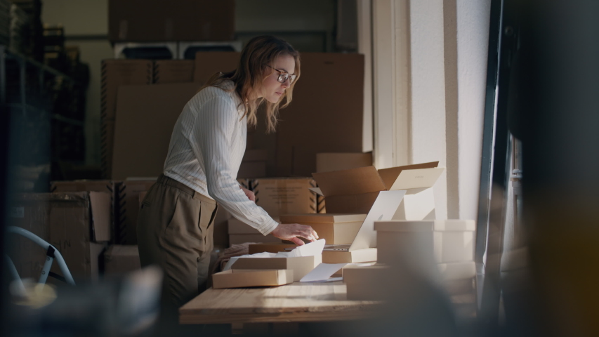 Woman packing the product as per the order displayed on her laptop. Online business owner working at the office, preparing the order for shipping to the customer.
 Royalty-Free Stock Footage #1052044090