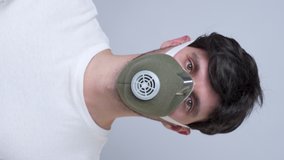 Vertical video. man in a respiratory mask, isolated on a gray background