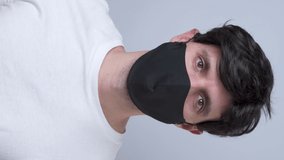 Vertical video. Man in a black medical mask, isolated on a gray background
