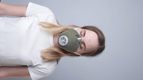 Vertical video. Woman in a respiratory mask, isolated on a gray background