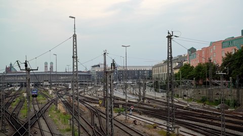 MUNICH, GERMANY - JUNE 25, 2018: Gimbal shot of Munich central railway station under grey cloudy sky. Deutsche Bundesbahn shot from bridge in summer time with red trains passing