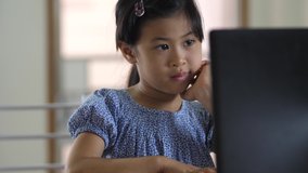 The asian girl looks with interest at the laptop. Distance learning, school online.