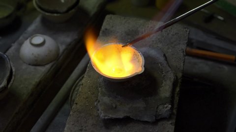 The jeweler melts gold in a liquid state in a crucible. Macro video. Craft jewelery making with professional tools. The process of making handmade jewelry, jewelry making. Metal melting