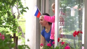 Russian family mother and little girl child on balcony / window are smiling and waving the flag of Russian. Self-isolation in quarantine, lockdown, stay at home, social distancing, coronavirus - Powered by Shutterstock - Get 15% off with code: PIKWIZARD15