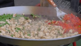 Super slow motion: chef cooking fried chicken meat pieces, peppers, peas in huge wok at summer food market - close up. Outdoor cooking, cookery, gastronomy and street food concept - Powered by Shutterstock - Get 15% off with code: PIKWIZARD15