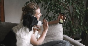 Young women sitting in a room-office on self-isolation and talking to someone on a video link with dog