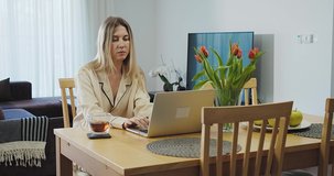 Young woman in pajamas with using laptop, drinking tea, dancing and listening to music. Stay at home. Weekend Family. Holidays time. Women's Day. 4K slow motion video.